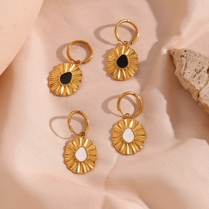 Detail view of golden sunflower earrings with black and white enamel on stone