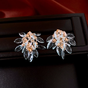 Detailed shot of golden rhombic tassel earrings with blue crystals on brown leather box