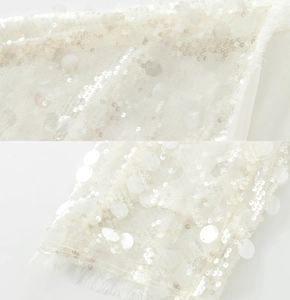 Detail of white blouse featuring sequin embroidery and delicate fringe trimming