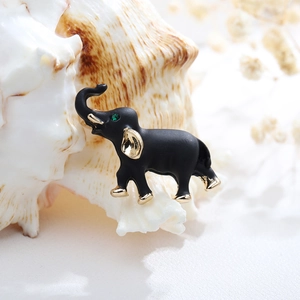 Vintage elephant brooch in matte black with gold accents and a green gemstone eye