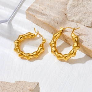 Detailed view of 18K gold plated bamboo design hoop earrings on decorative natural stones