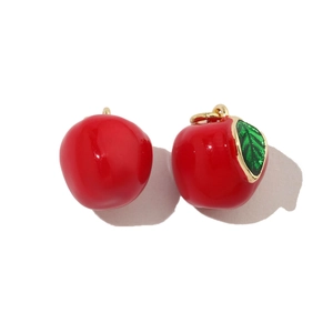 Detail of red apple enamel pendants with gold loops for DIY jewelry making