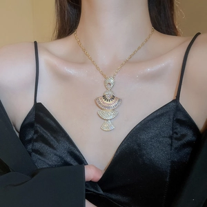 Detail of a fan-shaped gold pendant necklace with sparkling pink and white crystals