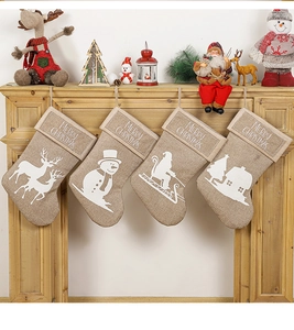Detail of four rustic burlap Christmas stockings with white festive silhouette prints