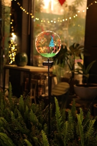 Detailed close-up of solar garden stake light with a glowing gnome and squirrel silhouette