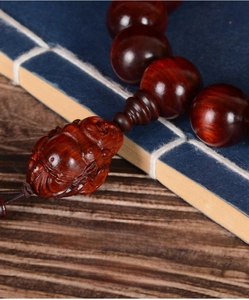 Detailed close-up of high-density red sandalwood prayer beads with carved rhino horn charm