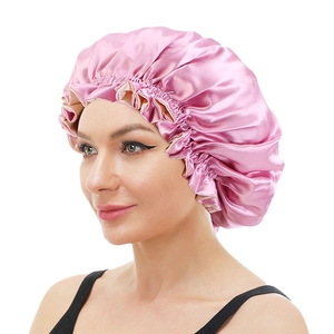 Detail of pink satin sleep cap with ruffled elastic band shown on a model