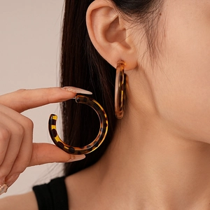 Macro shot of stylish tortoiseshell resin hoop earrings on model with a vintage aesthetic