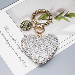 Portachiavi a cuore con strass brillanti e finiture dorate su sfondo di design