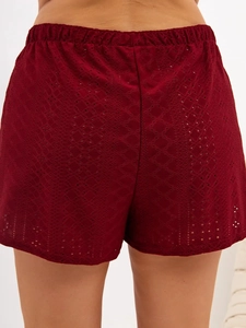 Detailed view of dark red lace hollow-out shorts with elastic waist and geometric patterns