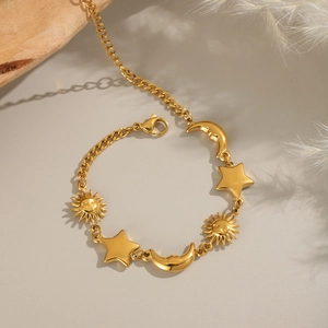Detailed close-up of 18K gold plated sun moon and star charms on a cuban chain bracelet