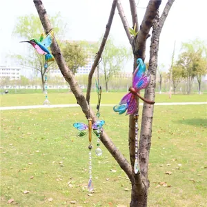 Detail of hummingbird crystal suncatcher hanging on a tree branch in a garden setting