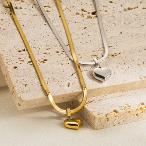 Polished gold and silver heart pendant necklaces on flat snake chain display