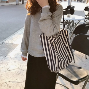 Classic large-capacity striped canvas tote bag shown worn on shoulder in street style