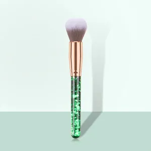 Detail of loose powder brush featuring a transparent handle filled with green glitter