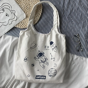 Detail of canvas tote bag with astronaut planet line art illustration in casual setting