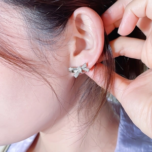 Elegant silver bow earrings with zircon stones shown as worn in a close-up portrait view