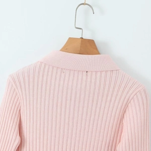 Détail d'un pull en maille côtelée rose avec col polo zippé et finition de qualité
