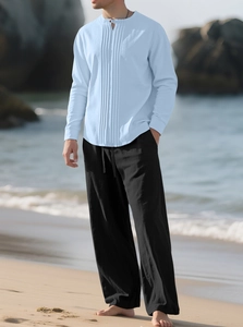 Herren-Set aus hellblauem Baumwoll-Leinen-Hemd und schwarzer Hose am sonnigen Strand