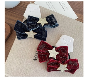 Close-up of velvet bow hair ties with shimmering stars in navy blue and dark red