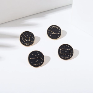 Détail de pin's zodiaque en émail noir avec motifs dorés pour Vierge, Taureau, Bélier et Gémeaux