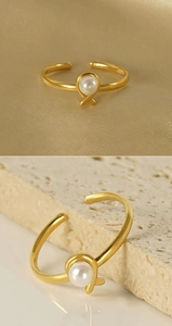 Detail of adjustable gold ring with elegant knotted design and white pearl inlay
