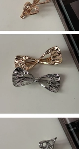 Detail of metal hair clip featuring polished heart and bow designs in gold and silver