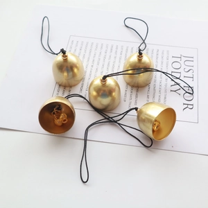 Five golden brass bells with black lanyards on a white decorative card background