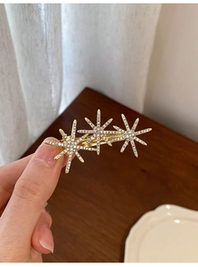 Detail of gold floral star hair clip with sparkling rhinestones in a refined design
