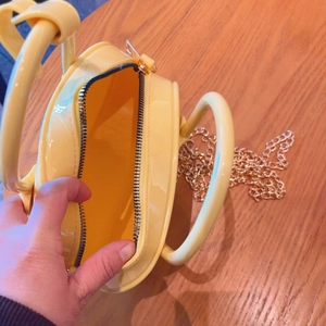 Detail view showing yellow PVC jelly bag interior with gold chain and black zipper