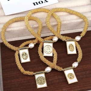 Golden beaded bracelet with pearl and shell religious pendant on beige fabric