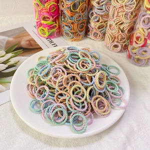 Bunte elastische Haargummis für Mädchen in sanften Macaron-Farben auf einem weißen Teller
