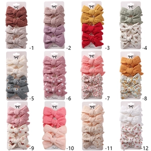 12 sets of children's fabric bow hair clips with floral and polka dot patterns on cards