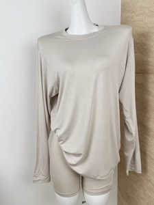 Detail of soft beige knit lounge set featuring long sleeve crewneck top and cycling shorts