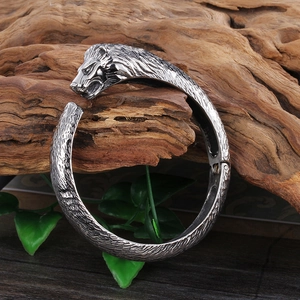 Détail d'un bracelet jonc tête de lion en argent vieilli sur bois avec feuilles vertes