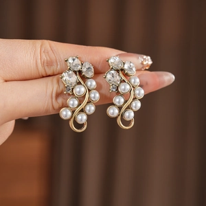 Detailed close-up of vintage bronze vine earrings with white pearls and crystal accents