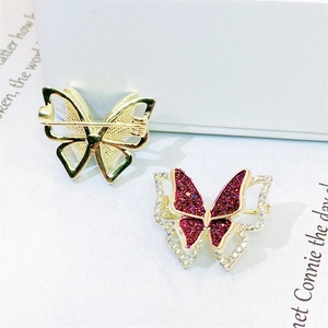Macro view of gold butterfly brooches with red gemstone and zircon inlay details