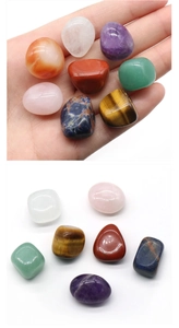 Detailed view of hand holding colorful polished irregular natural healing chakra stones
