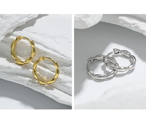 Macro detail of gold and silver S925 sterling silver hoop earrings on white rock