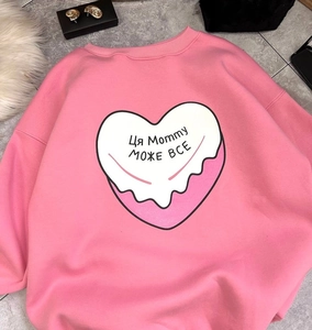Vue à plat du sweat rose avec imprimé cœur et lettrage blanc sur carrelage