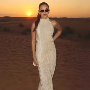 Chic beige pleated two-piece set featuring a halter top and pants in a desert sunset