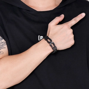 Close-up of men's black braided leather bracelet with unique metal clasp on model
