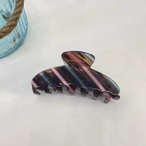 Detail view of large striped acetate hair claw clip in pink brown and blue with glossy finish