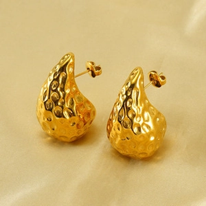 Macro detail of golden textured drop earrings with hammered finish on silk background