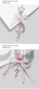 Detail of pink bow keychains with star charms, pearls and winged hearts on stone