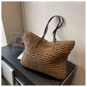 Detailed close-up of woven straw tote bag texture and brown leather shoulder straps