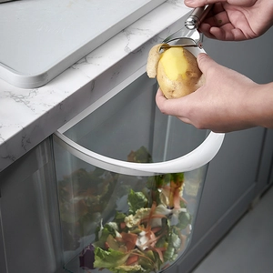 Wall-mounted transparent kitchen trash can hanging on cabinet for organic waste