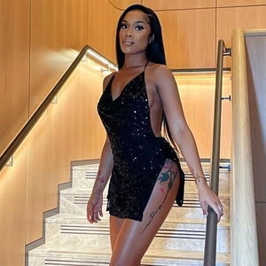 Detail showing backless black sequin mini dress with side slit on stairs