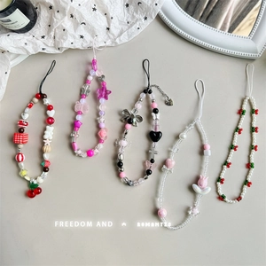 Handmade cherry bear phone charms with acrylic beads and pearls on a beige surface
