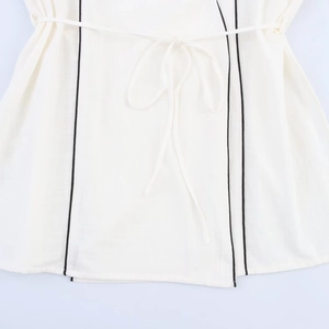 Detail of white cotton linen fabric with black vertical piping and a drawstring waist tie
